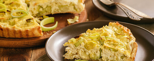 Quiche with leek and cheese on brown background.