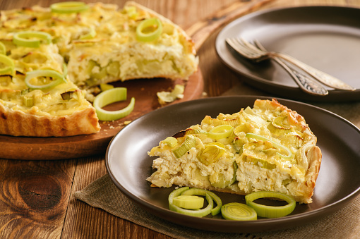 Quiche with leek and cheese on brown background.